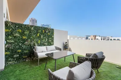 a patio with chairs and a table and a green wall at NEW! Spacious 2BHK with Maids room - JVC in Dubai