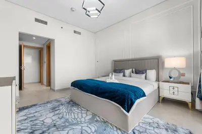 a bedroom with a large bed with a blue blanket at NEW! Spacious 2BHK with Maids room - JVC in Dubai
