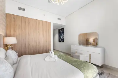 a bedroom with a large white bed with a wooden headboard at NEW! Spacious 2BHK with Maids room - JVC in Dubai