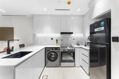 a white kitchen with a washer and dryer in it at Full Dubai Skyline View LUX 1 BR JVC in Dubai