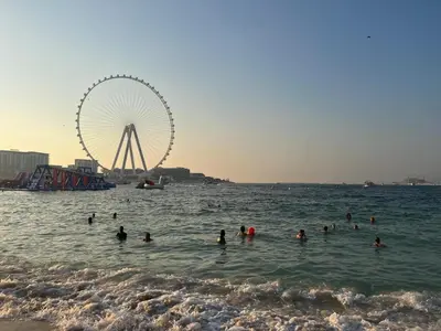 a group of people swimming in the ocean with a ferris wheel at Bahar 6 in Dubai