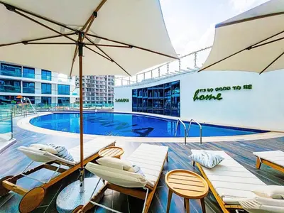 a pool with chairs and umbrellas in front of a building at Arjan Bright Studio w Resort Amenities Samana PV by Vibel in Dubai