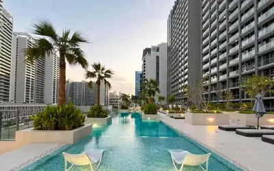 a pool with chairs and palm trees in a city at Vogue Downtown The Sterling by Omniyat, near Burj Khalifa and Dubai Mall, Studio Apartment with Balcony and Access to all Amenities in Dubai