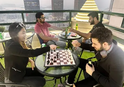 a group of people sitting around a table playing chess at The Junction Partition Room In Barsha Heights in Dubai