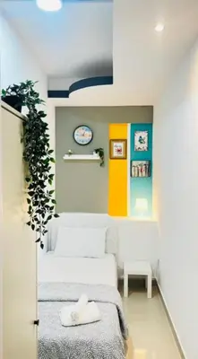 a room with two beds and a clock on the wall at Creative Partition Room in Barsha 1 Near Metro in Dubai