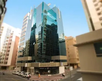 a tall glass building with cars parked in front of it at Creative Partition Room in Barsha 1 Near Metro in Dubai