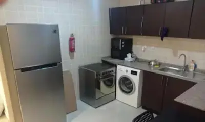 a kitchen with a refrigerator and a washing machine at Creative Partition Room in Barsha 1 Near Metro in Dubai
