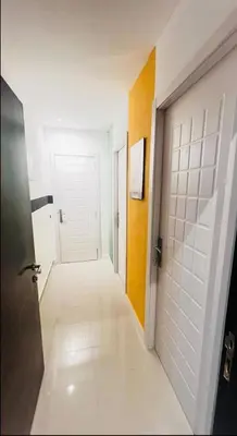 a hallway with a door and a room with white tiles at Ideal Partition Room in Barsha 1 Near Metro in Dubai