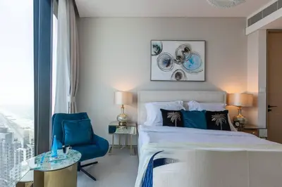 a bedroom with a large bed and a blue chair at Elegant 2BR Apt Address Beach Resort in Dubai