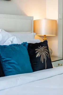 a bed with blue pillows and a palm tree pillow at Elegant 2BR Apt Address Beach Resort in Dubai