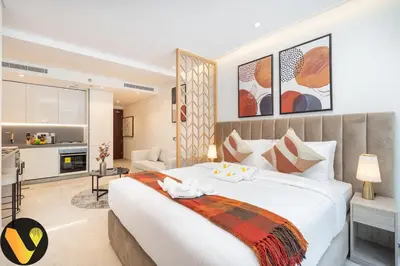 a bedroom with a large white bed and a living room at Vogue Downtown The Sterling by Omniyat, near Burj Khalifa and Dubai Mall, Studio Apartment with Balcony and Access to all Amenities in Dubai