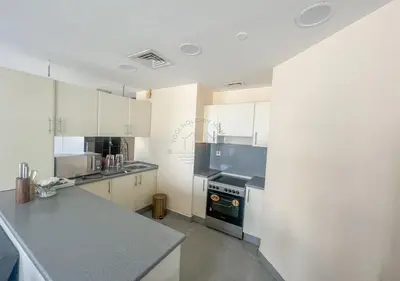 a kitchen with white cabinets and a stove top oven at Snug Studio With City Views, Perfect For Couples in Dubai