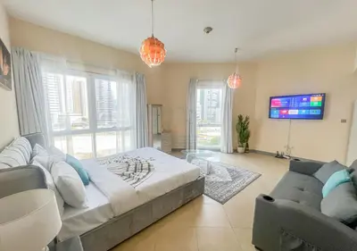 a bedroom with a bed and a couch and a tv at Snug Studio With City Views, Perfect For Couples in Dubai