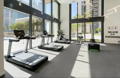 a gym with rows of tread machines in a building at Vogue Downtown Boulevard Heights near Dubai Mall and Burj Khalifa, Two Bedroom Apartment with balcony and Access to all Amenities in Dubai