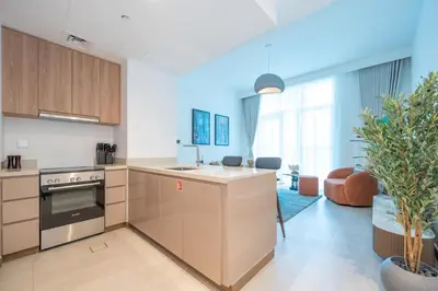 an open kitchen and living room with a couch at Sleek and Stylish 1BR Fully Furnished Apt in Dubai