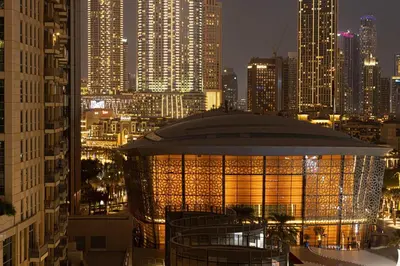 a lit up building in a city at night at Beautiful 2 BR Apartment next to Opera I Burj View in Dubai