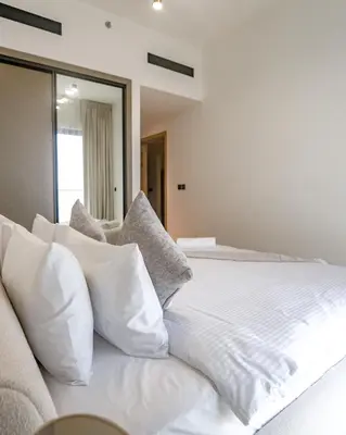 a white bed with white pillows on top of it at EasyGo- Peaceful 1BDR in Binghatti Heights JVC-01 in Dubai