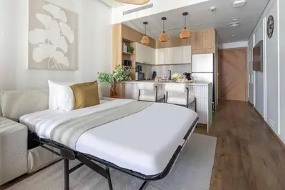 a bedroom with a large bed and a kitchen at Frank Porter - Rokane G25 in Dubai