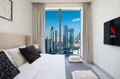 a bedroom with a white bed and a large window at LUXE - 2BR - Sea & City View - 5 Min to Dubai Mall in Dubai