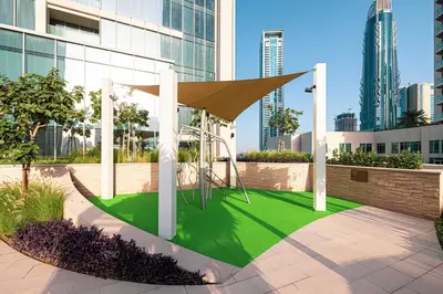 a park with a playground in a city with tall buildings at LUXE - 2BR - Sea & City View - 5 Min to Dubai Mall in Dubai