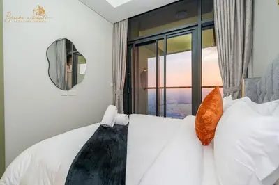 a bedroom with a white bed with a large window at Sea & Sunset View 2Bhk 5pax in Dubai