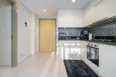 a kitchen with white cabinets and a yellow door at Sea & Sunset View 2Bhk 5pax in Dubai