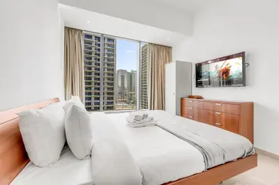 a bedroom with a white bed with a large window at Dubai Marina Elegant 1 BR on the Canal in Dubai