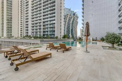 a patio with chairs and a pool and buildings at LUX Apt 5 min away from Burj Khalifa & Dubai Mall in Dubai