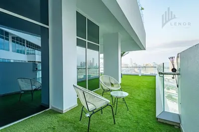 a balcony with green grass and chairs on a building at Modern 2BR Glowing Palm Trees Near Downtown in Dubai