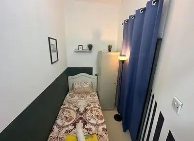 a small room with a bed and blue curtains at Gateway Partition Room in Barsha Mashreq Metro in Dubai