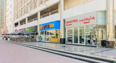 an empty shopping mall with tables and umbrellas at Cityscape Room In Tecom Near ICM Metro in Dubai