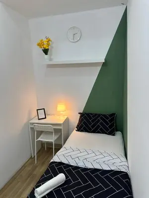 a bedroom with a bed and a table with a clock at Cityscape Room In Tecom Near ICM Metro in Dubai