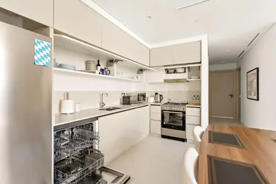 a kitchen with white cabinets and a wooden table at Silkhaus Beachside Spacious 2BDR in Marina Vista in Dubai