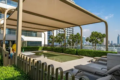 a patio with chairs and a pool on top of a building at Homes Beyond I Stylish 2BR Beachfront Bliss in Dubai