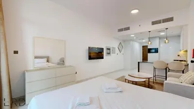 a white living room with a couch and a table at Modern Furnished Studio in Dubai