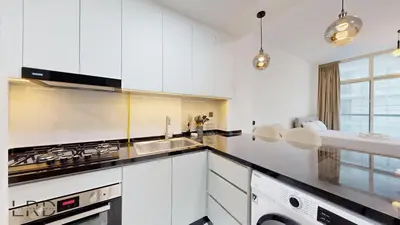 a white kitchen with a sink and a stove at Modern Furnished Studio in Dubai