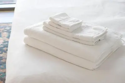 three white towels are stacked on a bed at Elegant 4BR Apartment with Burj Khalifa and Fountain Views Connected to Dubai Mall in Dubai