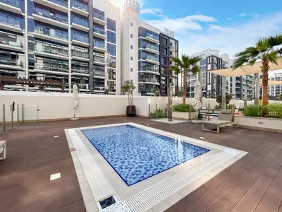an apartment patio with a swimming pool and buildings at Chic & Beautiful Home in the Heart of Meydan in Dubai