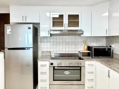 a kitchen with white cabinets and a stainless steel refrigerator at Homes 2 Retreat - Luxury & Spacious 1BR with Balcony in Business Bay in Dubai