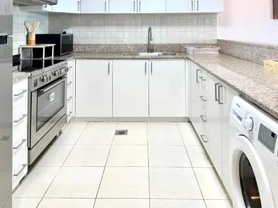 a white kitchen with a sink and a dishwasher at Homes 2 Retreat - Luxury & Spacious 1BR with Balcony in Business Bay in Dubai