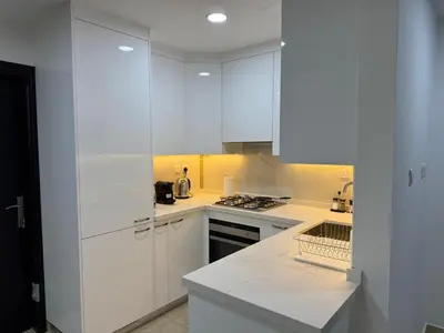 a white kitchen with white cabinets and a stove at Preatoni Tower - JLT by Golden Casa in Dubai