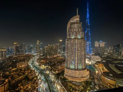 a tall building with blue lights on a city at night at Royal Vista - Luxury 4BR Apartment at Boulevard Point - Downtown in Dubai