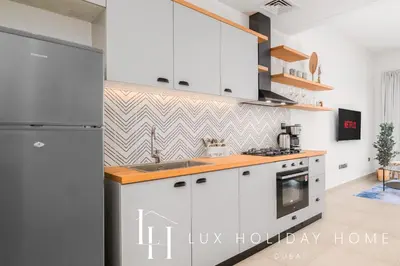a kitchen with white cabinets and a refrigerator at LUX The Collective Dubai Hills Suite in Dubai