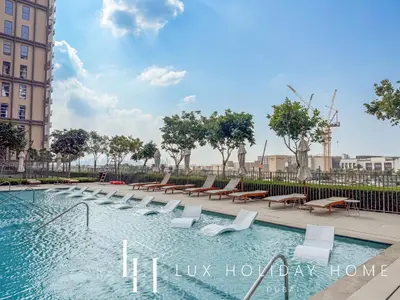 a swimming pool with lounge chairs and a building at LUX The Collective Dubai Hills Suite in Dubai