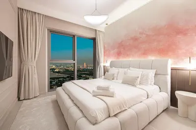 a bedroom with a large white bed with a large window at Downtown Chic 2 Bedroom Apartment I Dubai Mall Access I Views of Burj Khalifa from Pool I Free Parking, Gym, Pool & Wi-Fi I by Meerak in Dubai