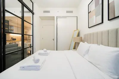 a bedroom with a large white bed with two towels at SettlerHomes - Idyllic Dubai Hills Stay Near Parkside in Dubai