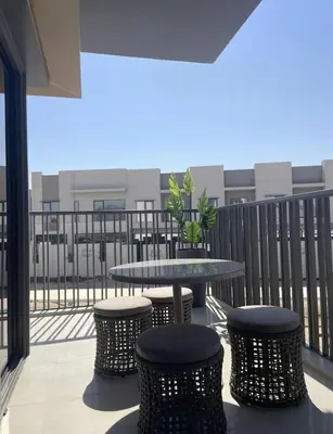 a patio with a table and stools on a balcony at Brand New Designer 1-Bedroom Apartment With Free Parking in Dubai