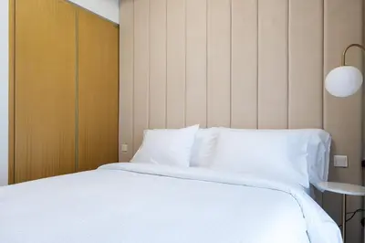 a bedroom with a white bed with a wooden headboard at Keyrock Living - Dubai Oasis with Balcony Views in Dubai