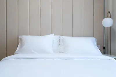 a white bed with white sheets and a lamp at Keyrock Living - Dubai Oasis with Balcony Views in Dubai