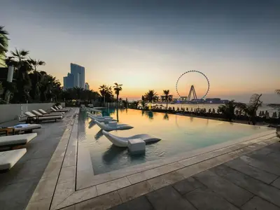 a pool with lounge chairs and a ferris wheel in the background at Sea-view 2BD apt with private beach in La Vie in Dubai